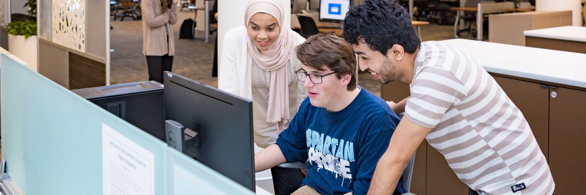 Three students collaborate at a computer in Kelvin Smith Library