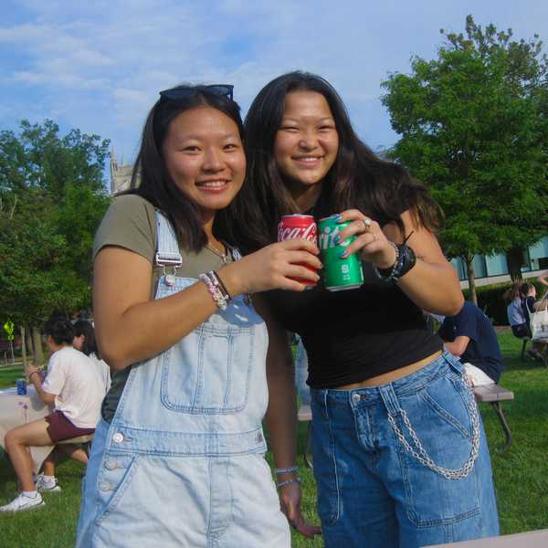 Two CWRU students posing with cans of soda and smiling.