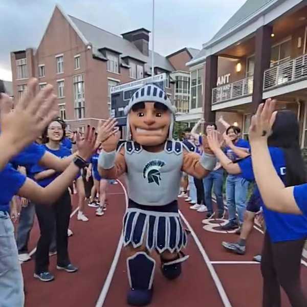 CWRU mascot Spartie raises his hands for high fives down a line of orientation leaders in a video from Discover Week.