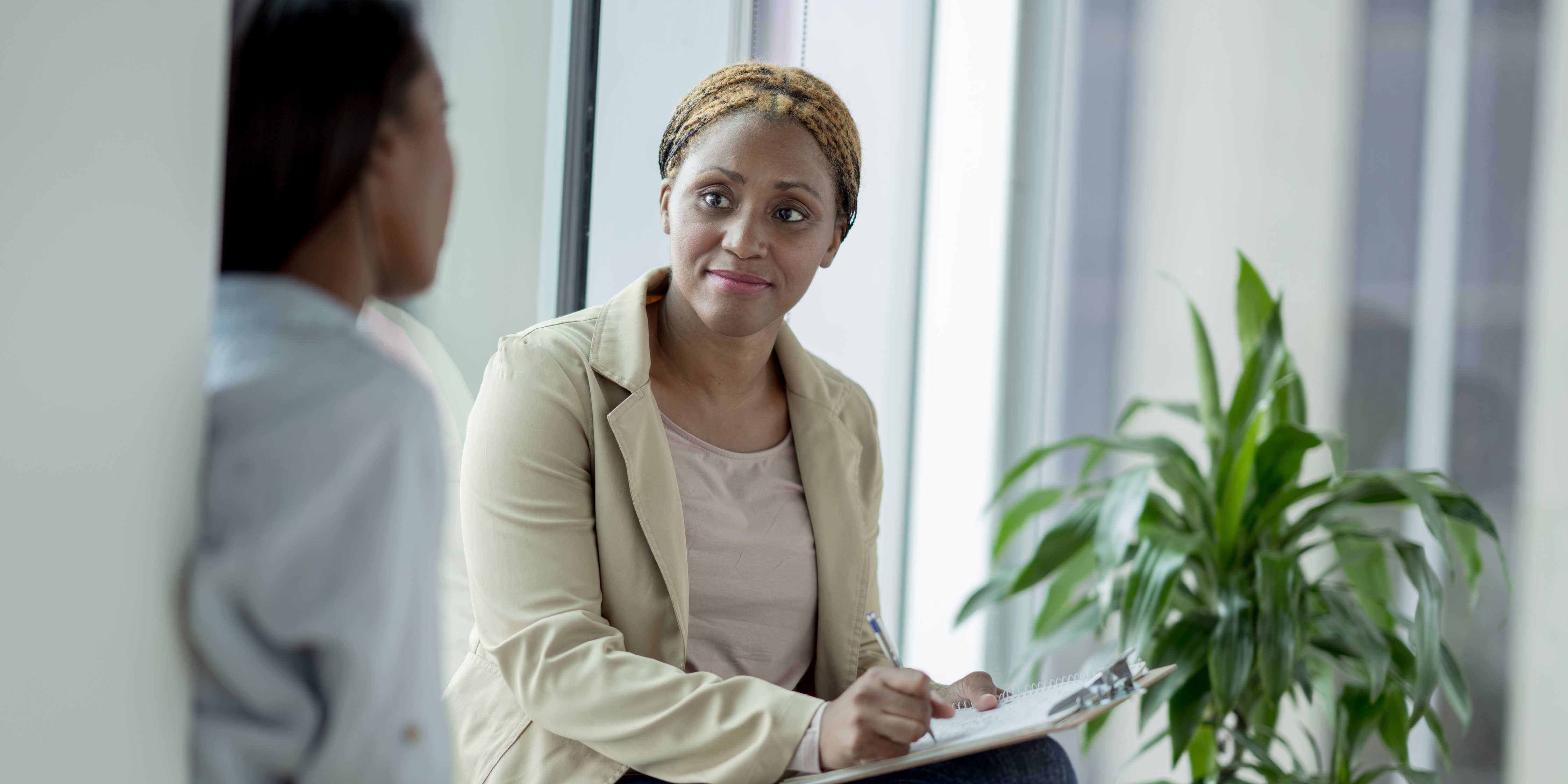 Photo of a student talking with a counselor, with the counselor facing the camera and taking notes
